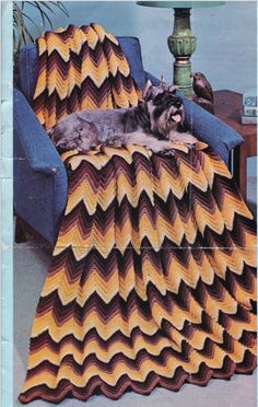 a dog laying on top of a couch next to a blanket that is made out of chevrons