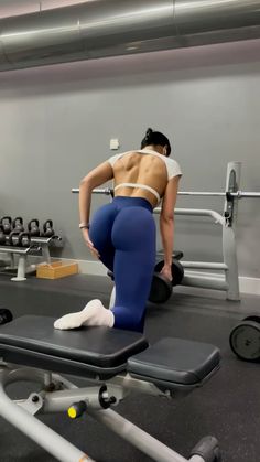 a woman in blue leggings is doing exercises on a bench with dumbbells