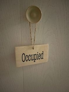 a wooden sign that says occupied hanging on the wall next to a cup and saucer