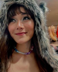 a woman wearing a fur hat and beaded necklace