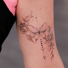 a woman's arm with flowers and a butterfly tattoo on the left side of her body