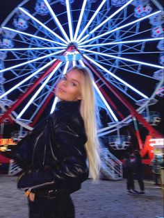 a woman is standing in front of a ferris wheel with her hand on her hip