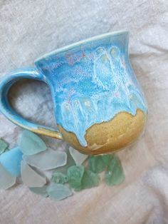 "A pretty mug for the days when you wish your toes were in the sand instead of slippers. ;) Made with white clay and glazed with a tan coat on the bottom and a series of blues and opal pink gloss over the top. Photo is color accurate! Handmade, wheel-thrown mug. The mug is approximately 4\" tall with a 3.25\" diameter. Holds approx. 10-12 oz. Please note your mug will be chosen from a batch of 5, so May differ slightly from the exact photo listing.  Everything is designed and handmade in Los Angeles, California. Check out my store for more and save by bundling purchases. I am always open to custom orders and with different colors. Feel free to reach out for more details! :) All purchases are protected or wrapped using reused or 100% recycled materials for maximum eco-friendliness.  Check o Pottery Photography, Pretty Mug, Beach Mug, Instagram Sales, Pink Gloss, Beach Pottery, Handmade Ceramics Pottery, Tan Coat, Pottery Pot