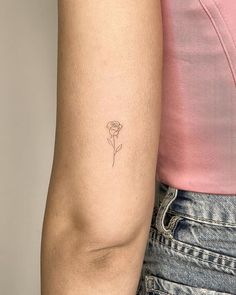 a woman's arm with a single rose tattoo on the left side of her arm