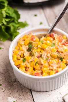 a white bowl filled with corn and topped with cilantro next to some parsley