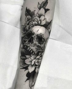 a black and white tattoo with flowers on the arm, skull and roses in the middle