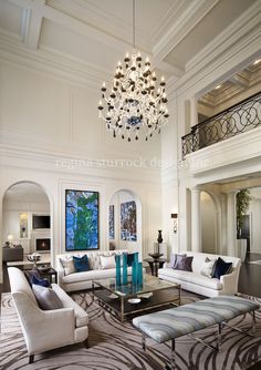 a living room filled with white furniture and a chandelier hanging from the ceiling