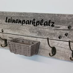 a wooden coat rack with two hooks and a basket hanging from it's side