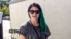 a woman with green hair and sunglasses standing in front of a trailer