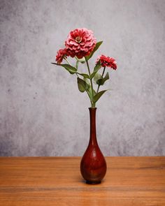 red flowers in a brown vase on a wooden table