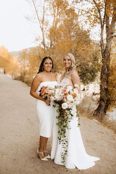 two women standing next to each other holding bouquets in their hands and posing for the camera