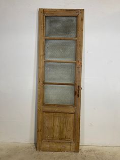 an old wooden door with glass on the front and side panels, against a white wall