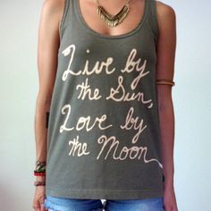 a woman wearing a tank top that says live by the sun, love by the moon