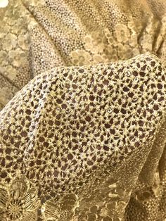 a close up view of an animal's head on a bed sheet covered in gold and brown flowers