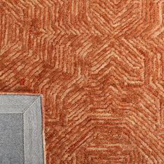 an orange and grey area rug next to a blue square on top of a wooden floor