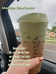 a person holding up a cup of coffee in the back seat of a car with words written on it