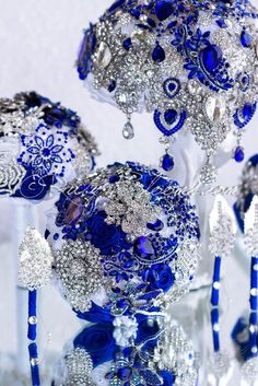 blue and silver ornaments are arranged on display in a glass vase with crystal balls attached to them