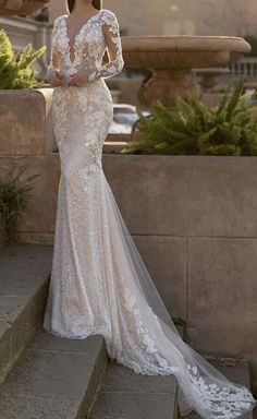 a woman in a wedding dress standing on some steps with her back to the camera