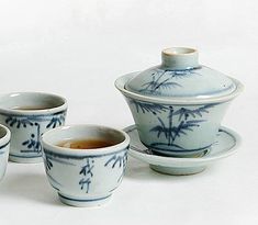 four cups and saucers with blue designs on them