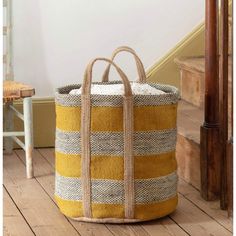 a large yellow and white basket sitting on top of a wooden floor next to stairs