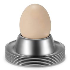 an egg sitting on top of a metal object with a white background and silver base