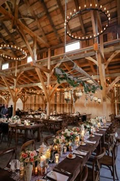 the inside of a barn with tables and chairs set up for a wedding reception, surrounded by chandeliers