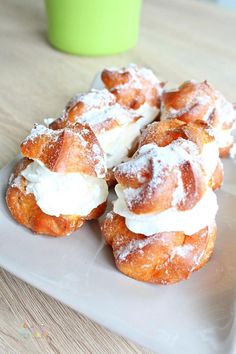 powdered sugar covered doughnuts on a white plate