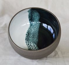 a black and white bowl with blue swirls in the center on a white tablecloth