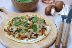 a pizza sitting on top of a wooden cutting board next to a knife and fork