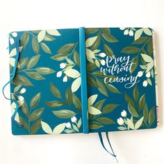 a blue notebook with green leaves and white flowers on it that says pray without ceasity