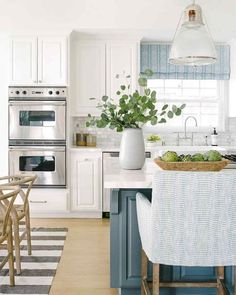 a kitchen with white cabinets and blue island in front of an oven, sink, dishwasher and stove