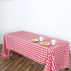 a red and white checkered table cloth with two plates on it sitting on a wooden floor