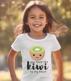 You Hold the Kiwi to my Heart Shirt, Fruit Youth Shirt, Pun Kids Shirt, Kids T-Shirt, Unisex Toddler Shirt, Kiwi Kids Shirt Let your child's fashion journey begin with the Bella Canvas 3001 Youth T-Shirt - the perfect blend of style and comfort for our young fashion icons. 🌟 Premium Fabric: Crafted with the utmost care, the 3001 Youth T-Shirt features a premium blend of cotton and polyester, ensuring a soft and cozy feel against your child's skin. They'll stay comfortable and confident all day long. 🌟 Fashionable Fit: Designed to suit the tastes of young trendsetters, this youth tee boasts a modern unisex fit, catering to both boys and girls. Its contemporary silhouette ensures they look effortlessly stylish wherever they go. 🌟 Versatile Styling: From playground adventures to family out Cute Short Sleeve Shirt With Funny Text, Cute Short Sleeve Shirt With Slogan, Cute Short Sleeve Shirt With Name Print, Youth Shirt, Fashion Icons, Family Outing, Heart Shirt, Young Fashion, Premium Fabric