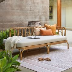 a day bed sitting on top of a rug next to a wooden wall and potted plants