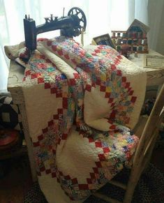 an old sewing machine sitting on top of a table next to a quilted blanket