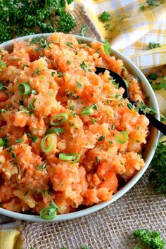 a bowl filled with carrots and green onions on top of a cloth covered table