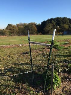 a wire fence in the middle of a grassy field