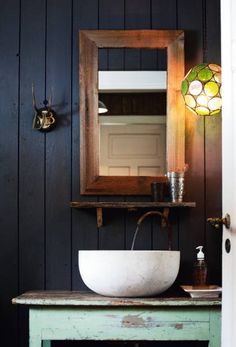 a bathroom sink sitting under a mirror on top of a wooden counter next to a light