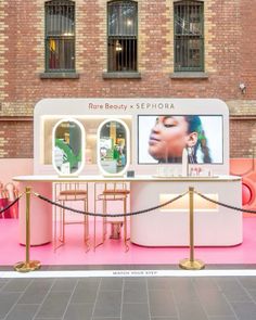 a display in front of a brick building with pink carpeting and gold barriers around it