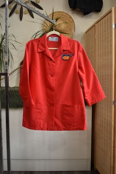 1970s retro cherry red IGA supermarket uniform work shirt // workwear jacket with wide sleeves, retro butterfly collar, and patch pockets. Looks like something a gas station attendant, butcher, or mechanic would wear. Loose tented fit. By Angelica. Wash and wear! Technically womens but fits like a unisex large Shoulders 18" Chest 48" Sleeve 19" Arm Hole 11" Length 29.5" Orange Workwear Top With Pockets, Retro Red Tops With Pockets, Retro Outerwear For Office, Red Tops With Pockets For Workwear, Red Workwear Top With Pockets, Red Cotton Outerwear For Work, Vintage Outerwear With Pockets And Short Sleeves, Vintage Orange Outerwear For Workwear, Retro Cotton Outerwear For Work