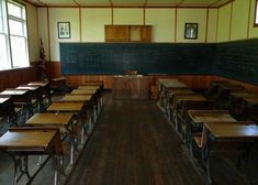 an empty classroom with wooden desks and blackboard