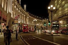 a busy city street at night with double decker buses