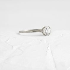 a white gold ring with a single diamond in the center on a textured surface