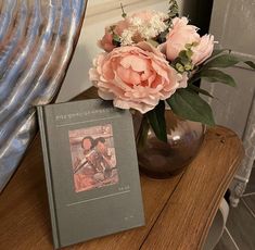 a vase filled with pink flowers next to a book