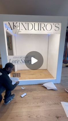 a man kneeling down in front of a display case with papers on the floor next to it