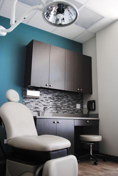 a room with a chair, sink and cabinets in it that has a clock on the wall