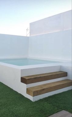 an outdoor hot tub with steps leading up to the pool and grass on the ground