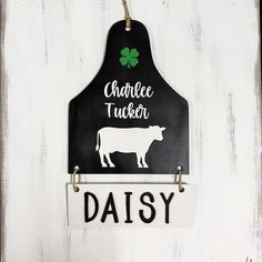 a black and white sign hanging on the side of a building with a cow in it