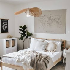 a bed with white sheets and pillows in a bedroom next to a plant on the wall