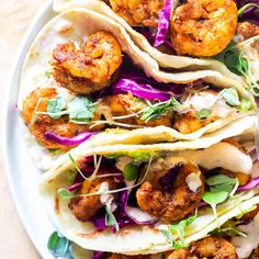 shrimp tacos with cabbage slaw and cilantro sauce on a white plate